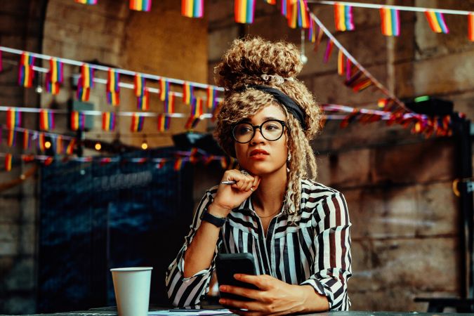 Black woman in stripe shirt texting in cafe