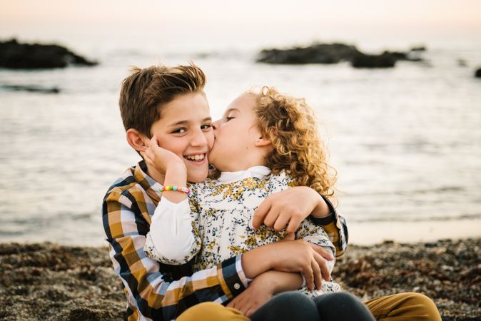 cute girl kissing her brother at beach