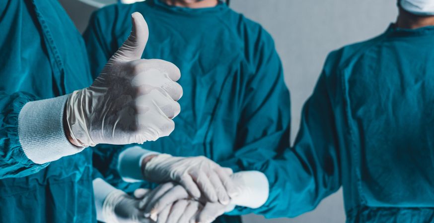 Wide shot of medical staff in scrubs with thumbs up