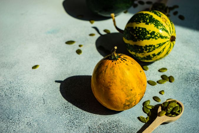 Two colorful mini squash on counter top with spoons of seeds