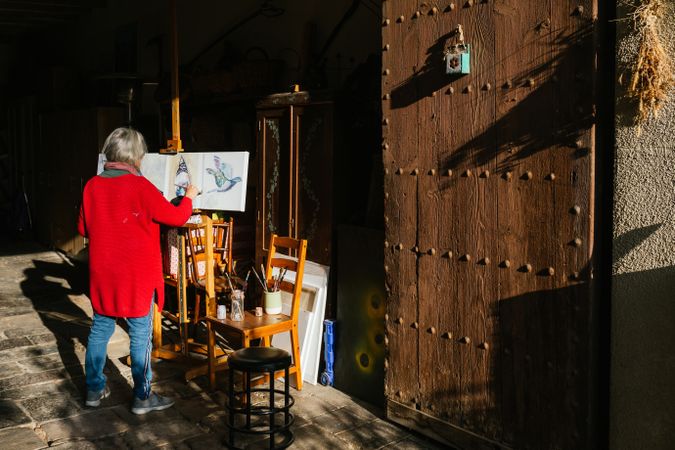 Anonymous woman painting on canvas in countryside