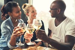 Three good friends toasting with wine glasses in a bright restaurant