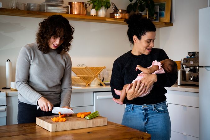 Young family in the kitchen chopping vegetables with baby