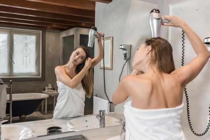 Woman drying her hair in bathroom
