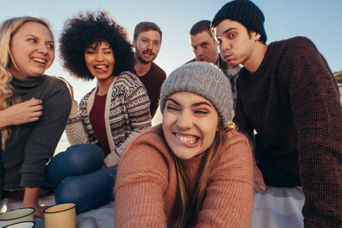 Group of young people making funny faces while taking selfie on the beach