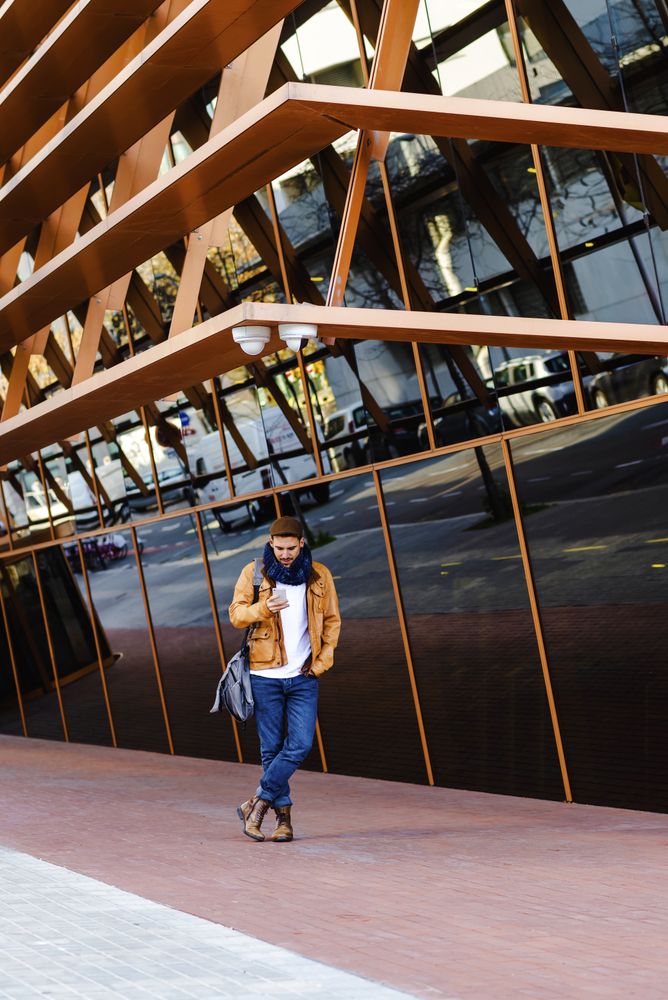 Stylish guy using smartphone outside modern building