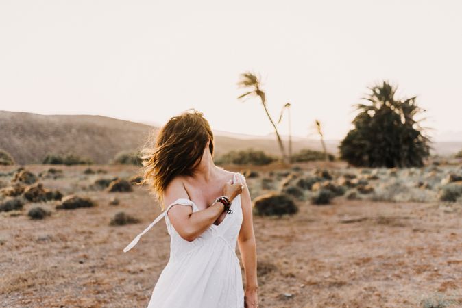 Woman in white dress in dry field in sunlight