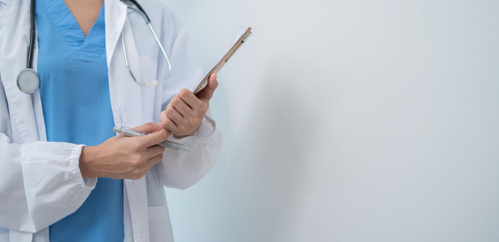 Doctor standing in light hospital room with copy space, wide