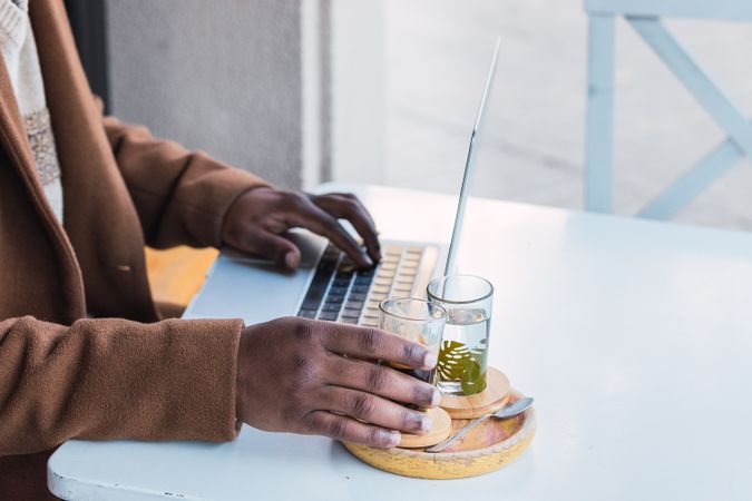 Crop Black man with espresso and glass of water in cafe
