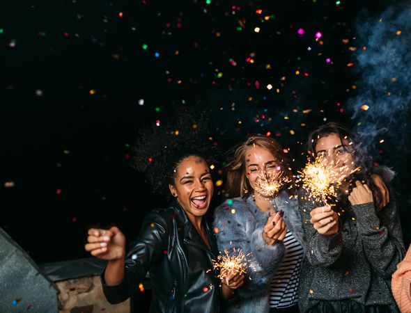 Multi-ethnic group of fun women at a party with confetti and sparklers