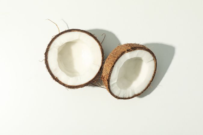 Halves of coconut on blank background, top view