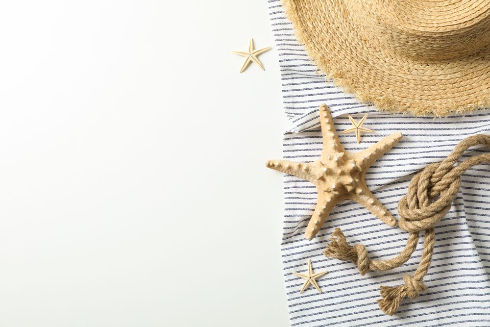 Tablecloth with straw hat, starfishes and sea rope on plain background, space for text and top view. Summer vacation