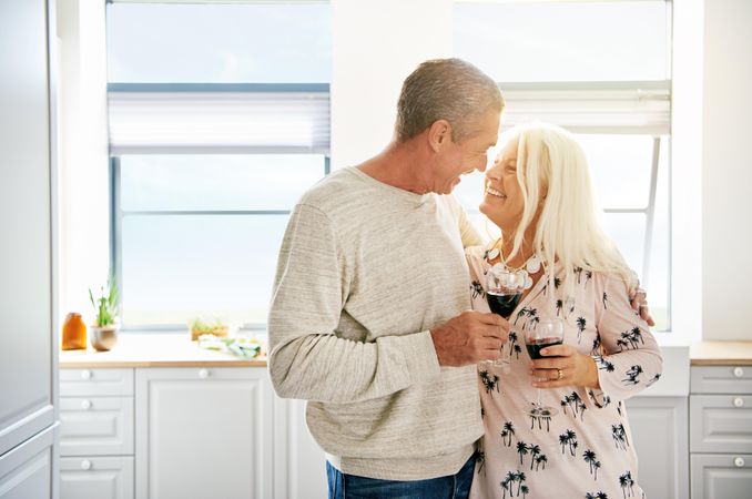 Happy couple drinking wine in a bright kitchen