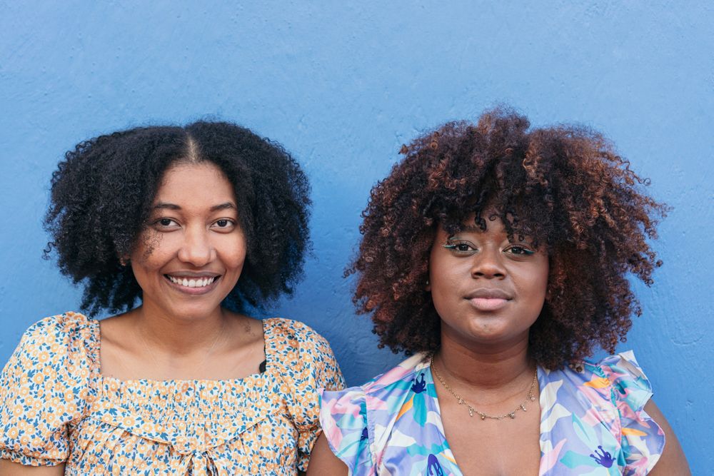 Portrait of two women standing on a blue wall