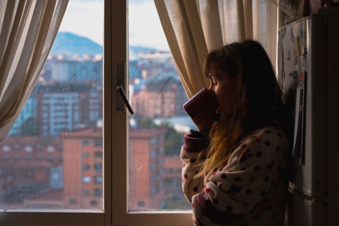 Woman enjoying hot beverage near fridge