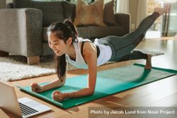 Smiling woman exercising at home and watching training videos on laptop bEpno4