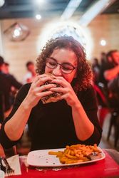Young woman eating burger in cafe