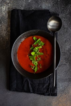 Top view of gazpacho soup served in dark bowl on counter
