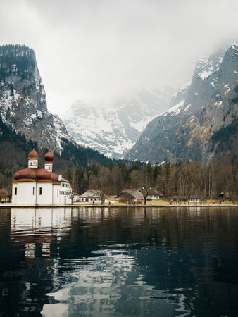 beautiful landscape with various buildings, snowy mountains, forest, cloudy sky and natural lake in the background of Königssee, Germany.
