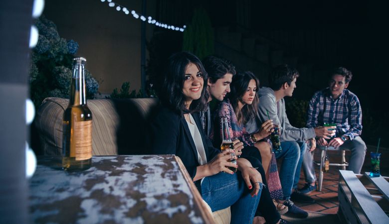 Woman holding beer with her friends talking in a party