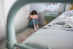Unrecognizable girl crying on the floor in her bedroom