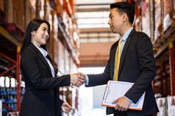 Two professional colleagues in warehouse shaking hands