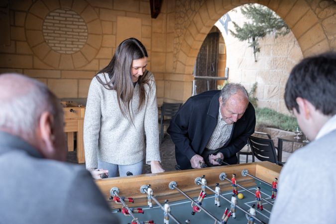 A granddaugther and his grandfather are playing table football game and having fun together