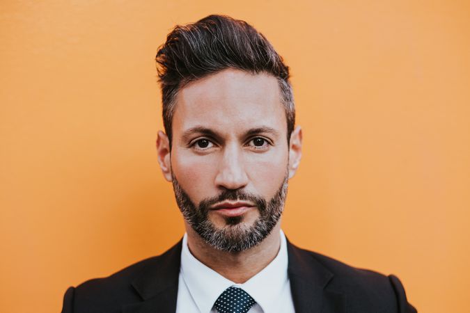Adult stylish man in costume near orange wall