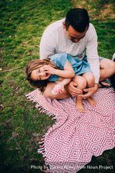 Daughter sits in father’s lap at the park a0LYe5