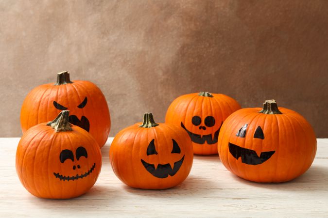 Funny halloween pumpkins against brown background, space for text