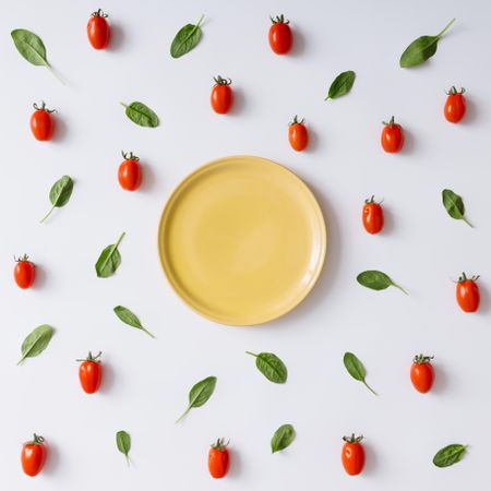 Yellow plate on tomato and basil pattern on light background