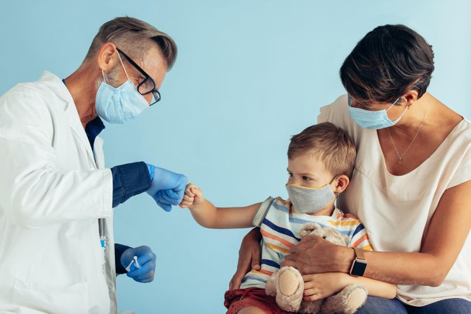Male doctor greeting small patient with a fist bump