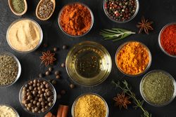 Glass bowls full of spices arranged on dark table