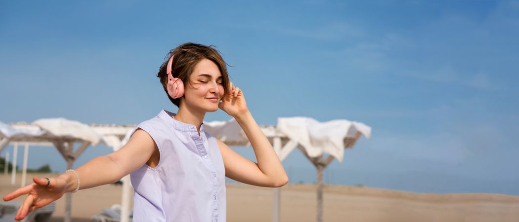 Woman listens to music with headphones outdoors
