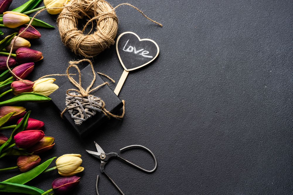 Tulips and present with scissors and string on dark counter