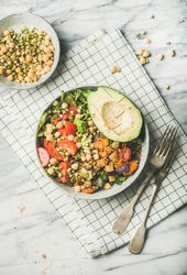 Healthy vegan lunch bowl with avocado, sprouted grains, vegetables, on checkered napkin