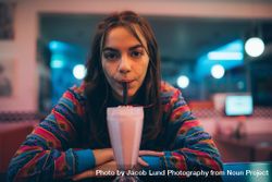 Woman in a diner drinking a milkshake from a straw in be7Xp5
