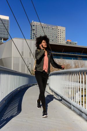 Woman with afro hair looking at her phone while walking.