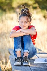 Little girl sitting on bench and clasping knees