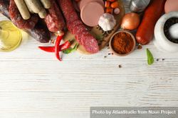 Selection of cured meats with peppers and spices on wooden background, copy space 56qkd0