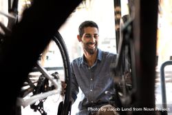 Smiling man in workshop looking at bicycles 5zdXjb