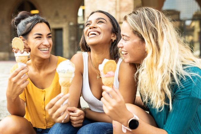 Three cheerful multi-ethnic women eating ice cream in Italy