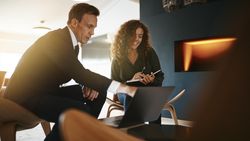 Man and woman working together taking notes over a laptop