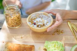 Unrecognizable mother and kid preparing yogurt with granola in park