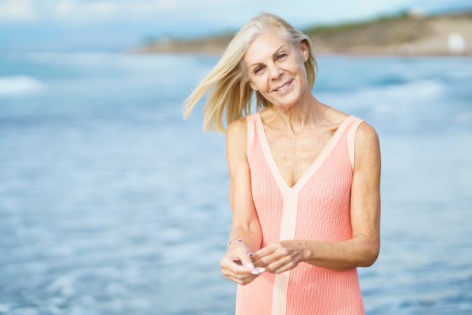 Calm happy older woman standing near coast