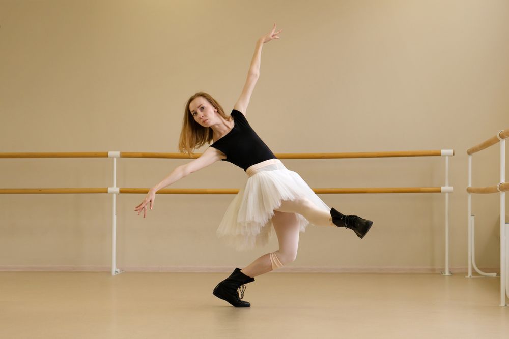 Ballerina in shoes and tutu, extending arm gracefully