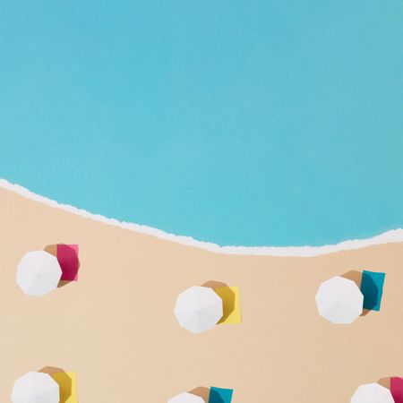 Aerial view of sun umbrellas and multicolored towels on sand with water