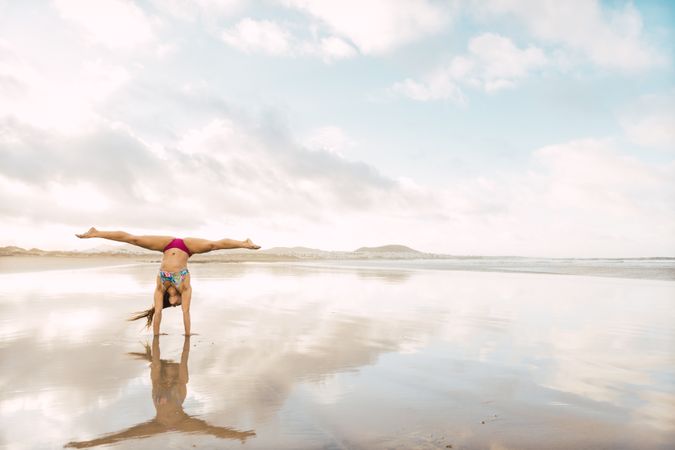 Woman doing handstand near sea