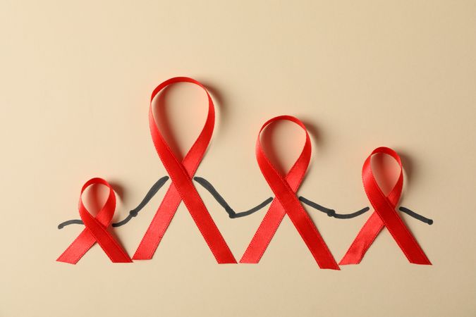 Awareness red ribbons on beige background, copy space