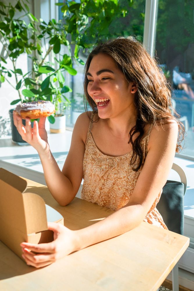 Woman enjoying tasty donut in cafe